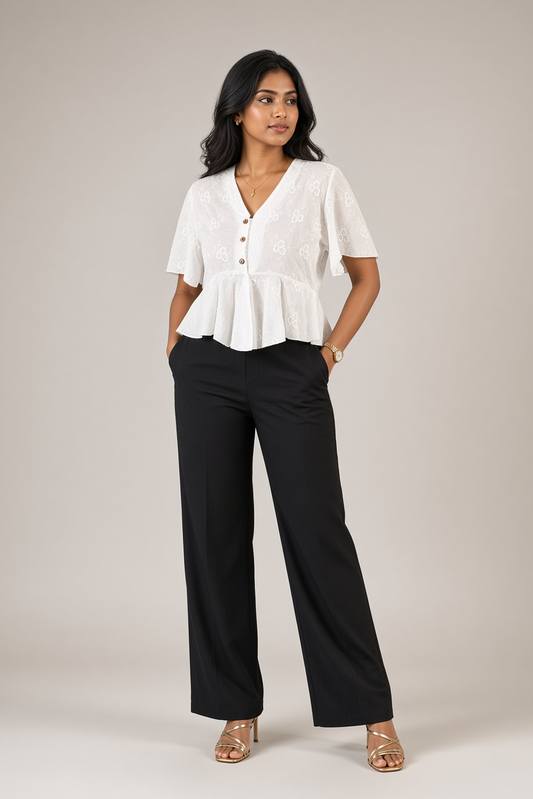 Petal Eyelet Top: white cotton eyelet peplum top with a V-neck and flutter sleeves, worn with black trousers, front view