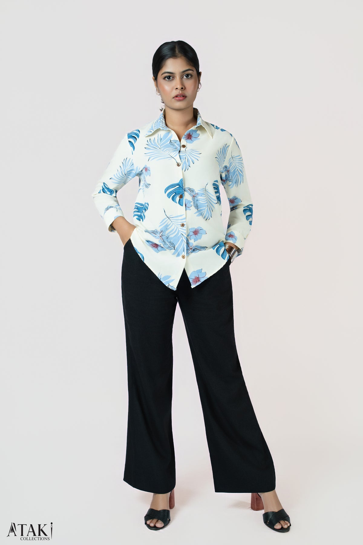 Capri Leaves Shirt: cream long-sleeve shirt with a blue tropical leaf print, worn with black trousers, front view