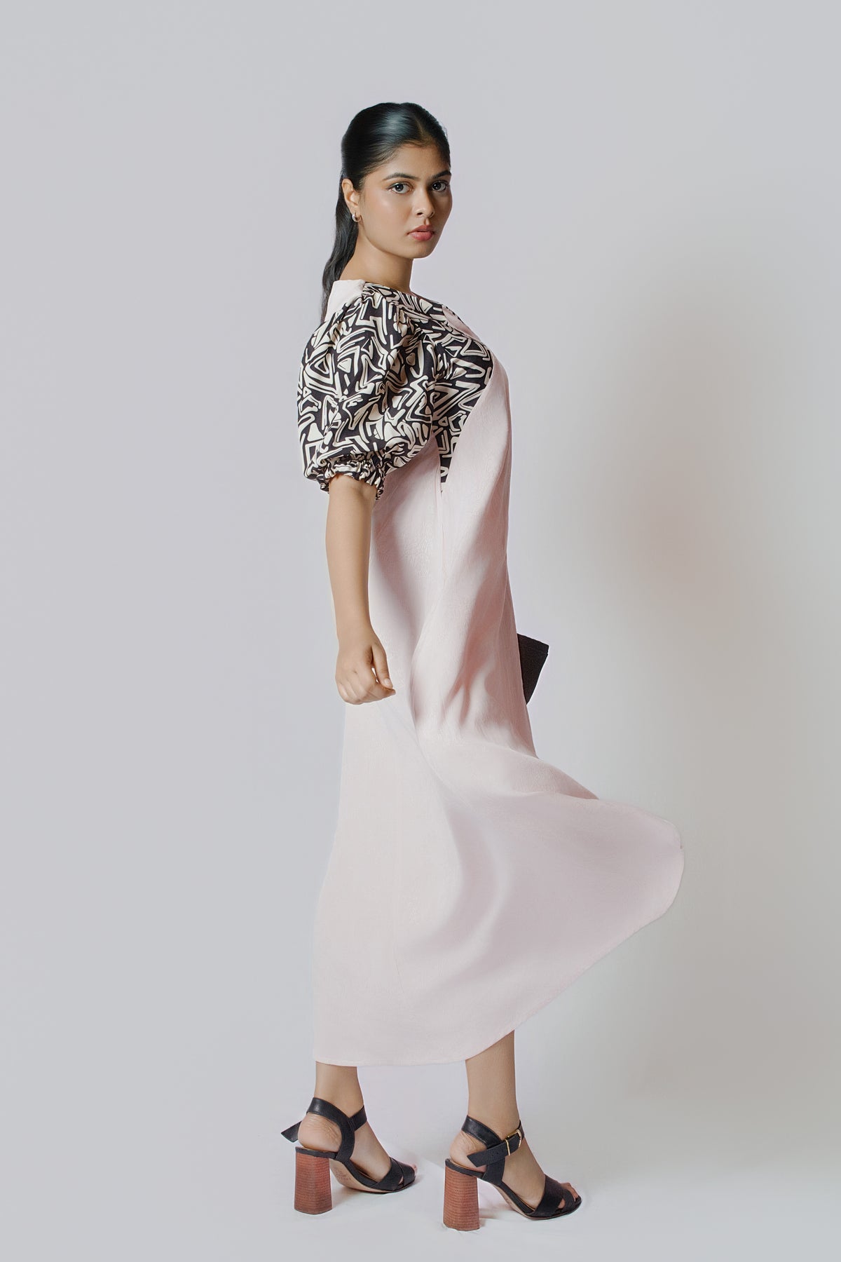 Luna Contrast Midi: pale blush midi dress with black and white patterned puff sleeves, side view, skirt in motion