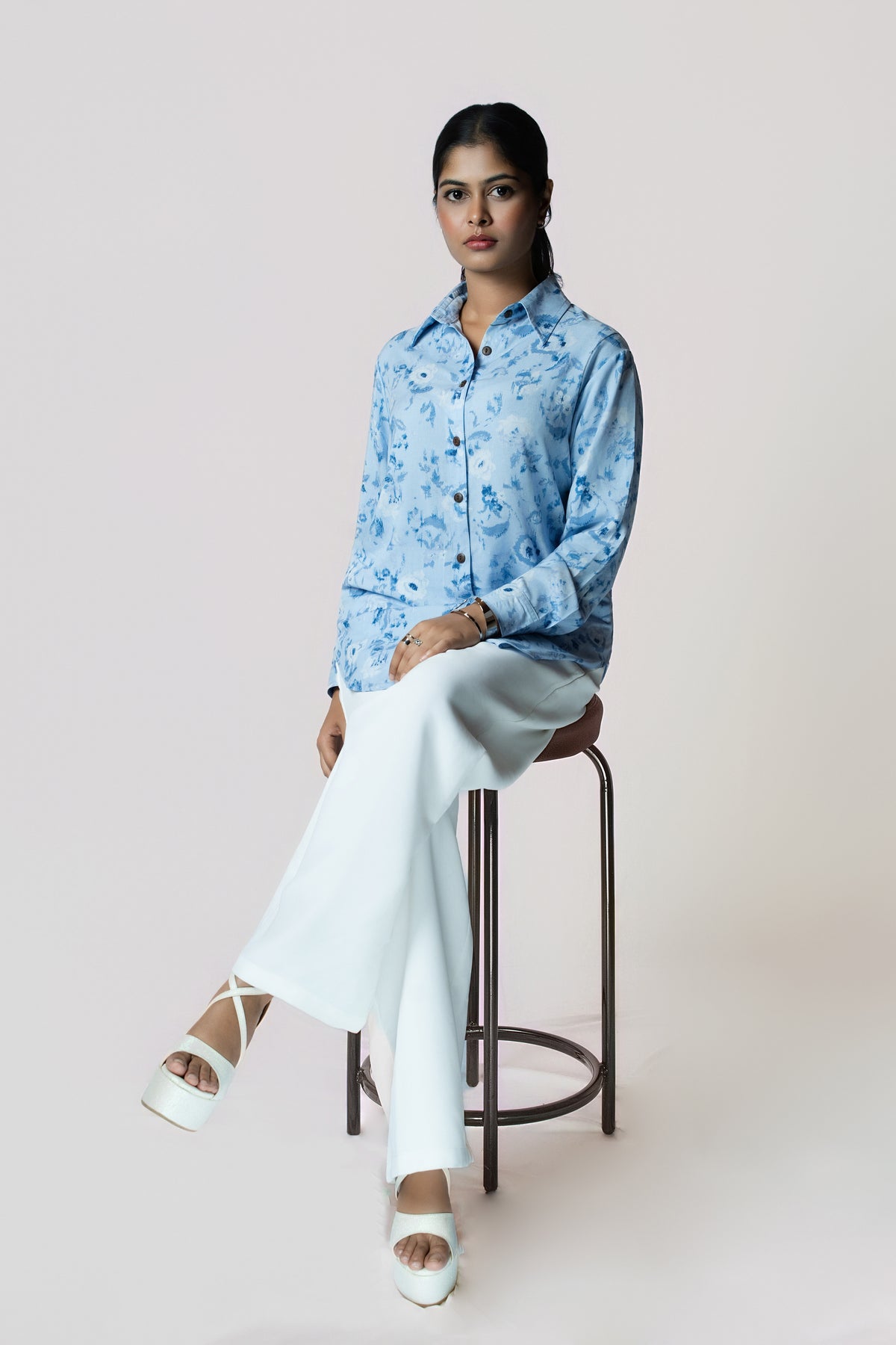 Skyline Bloom Shirt: light blue floral-print long-sleeve shirt, worn with white wide-leg trousers, seated view