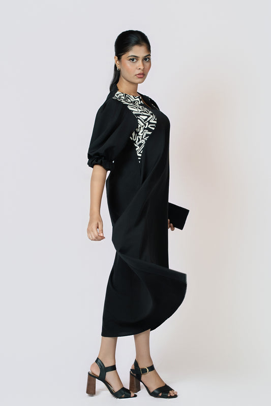 Monochrome Muse Midi: black puff-sleeve midi dress with black and white print trim at the neckline, side view, walking