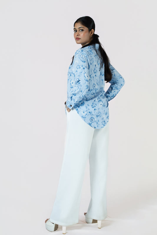 Skyline Bloom Shirt: light blue floral-print long-sleeve shirt, worn with white wide-leg trousers, side view