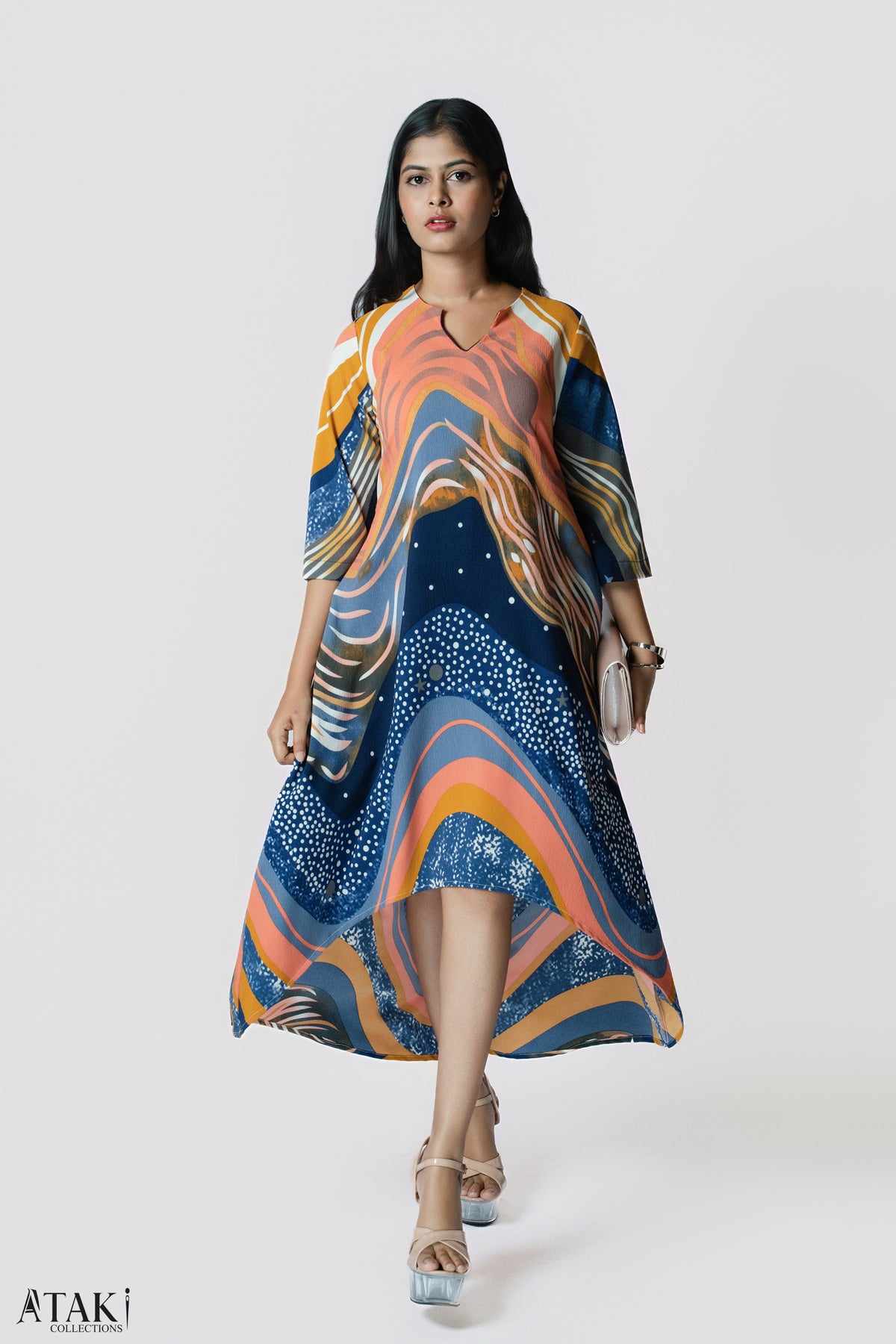 Model walking in a flowing navy, orange and mustard wave-print tunic dress