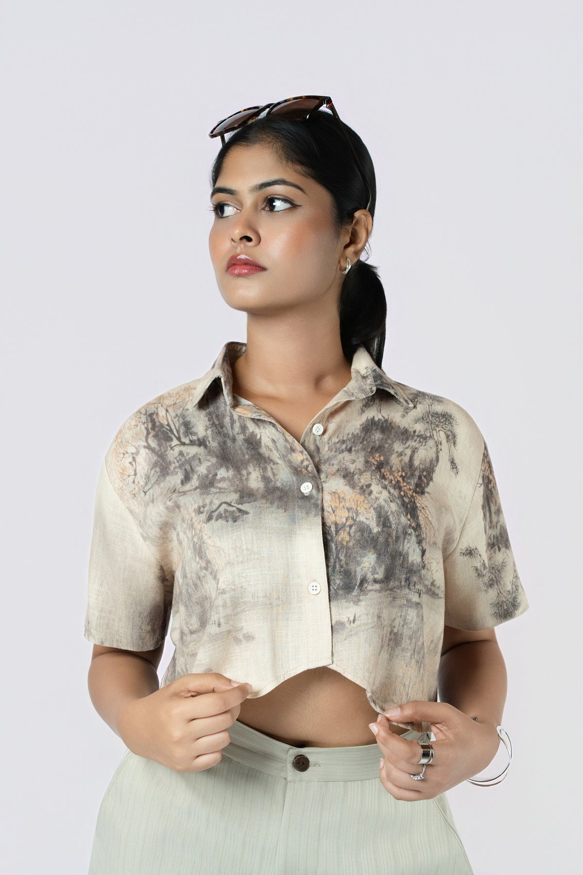 Willow Mist Crop Top: beige and grey brushstroke-print cropped cotton shirt with short sleeves, worn with sage trousers, close-up of the collar and cropped hem