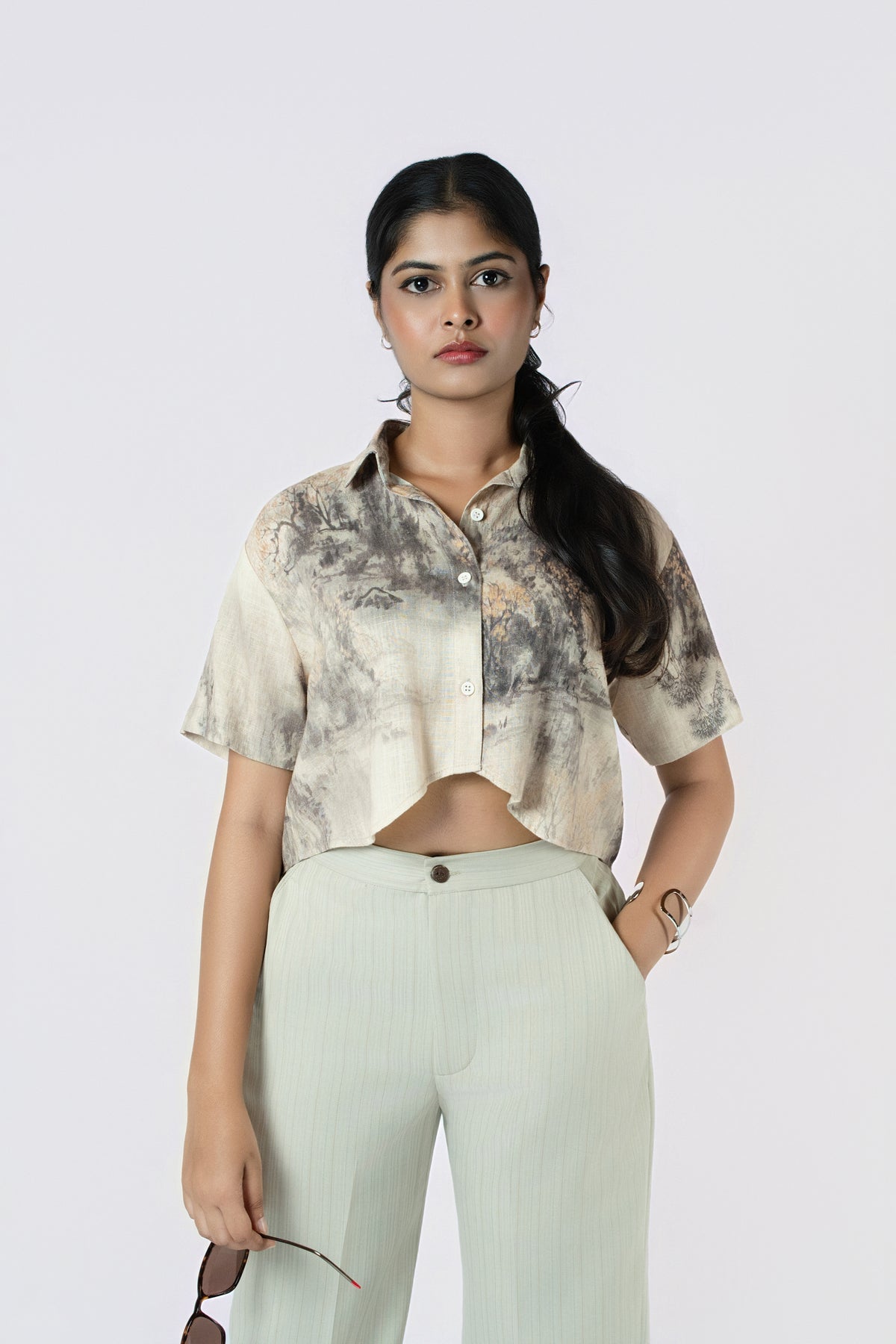 Willow Mist Crop Top: beige and grey brushstroke-print cropped cotton shirt with short sleeves, worn with sage trousers, close-up front view
