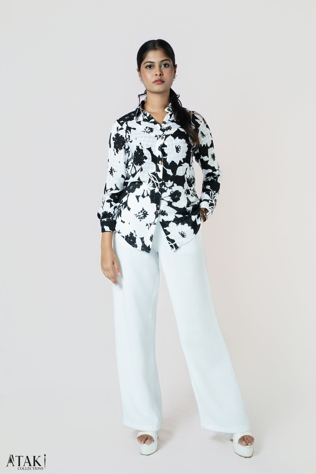 Mono Bloom Button-Up: black and white bold floral-print long-sleeve cotton shirt, worn with white wide-leg trousers, front view