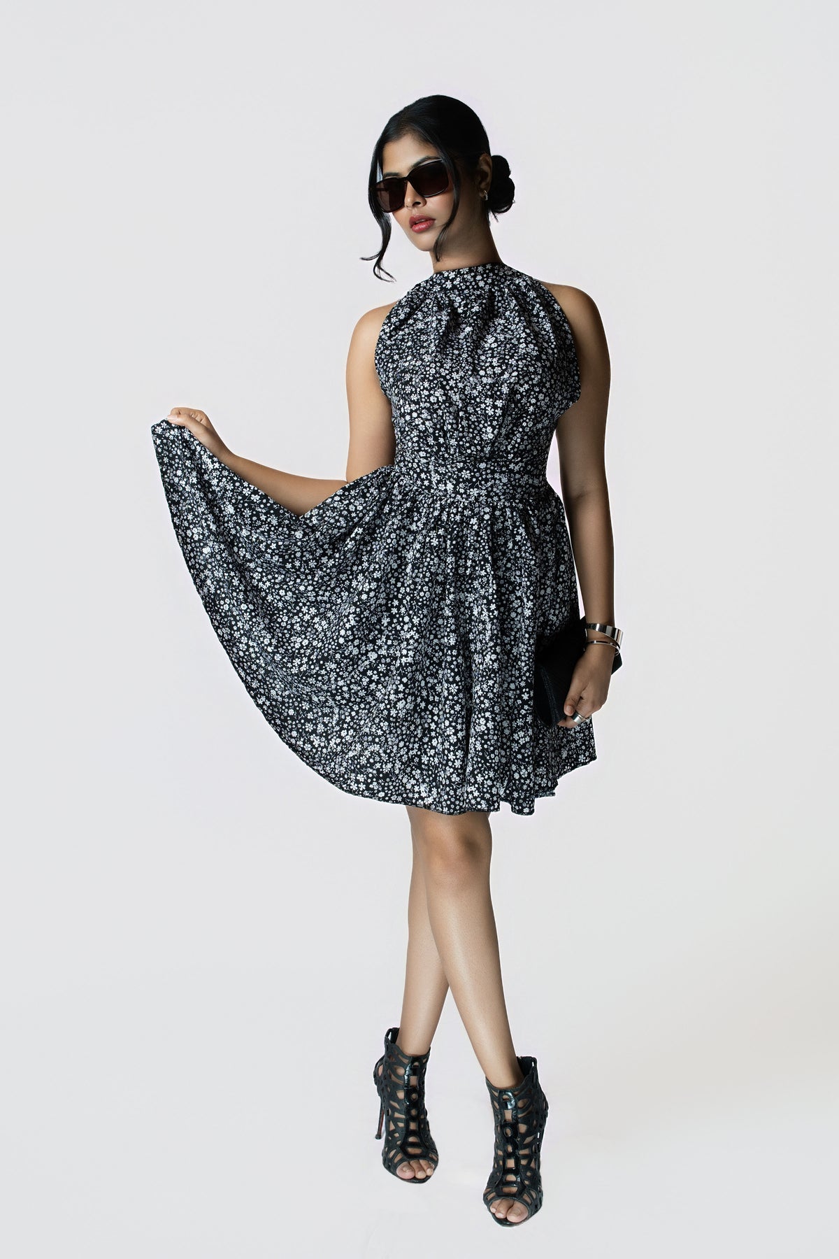 Noir Meadow Halter Dress: black and white ditsy floral halter-neck mini dress with a cinched waist, front view holding out the skirt