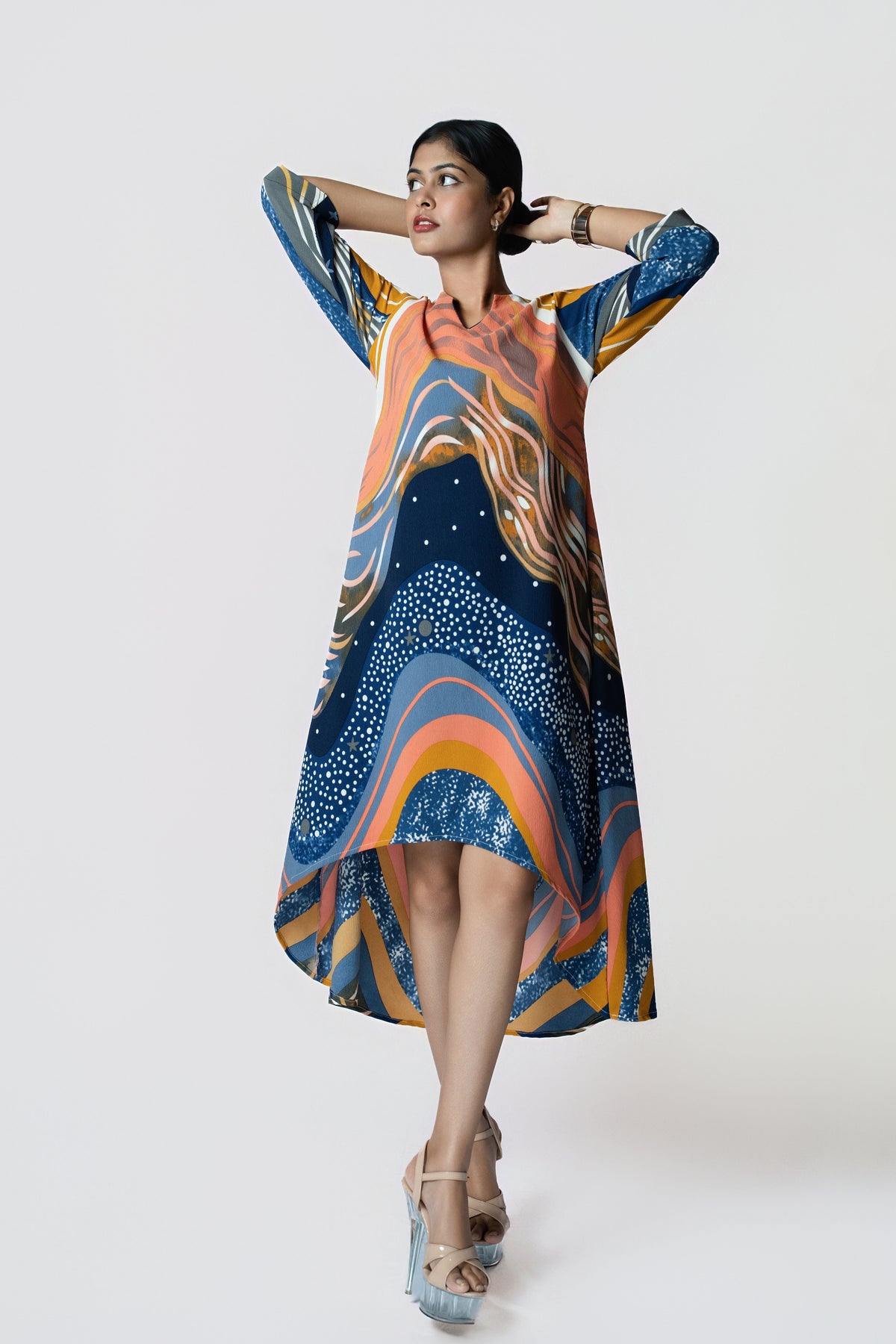 Stardust Flow Tunic: flowing tunic dress in a navy, orange and mustard wave print with a high-low hem, front view, arms raised