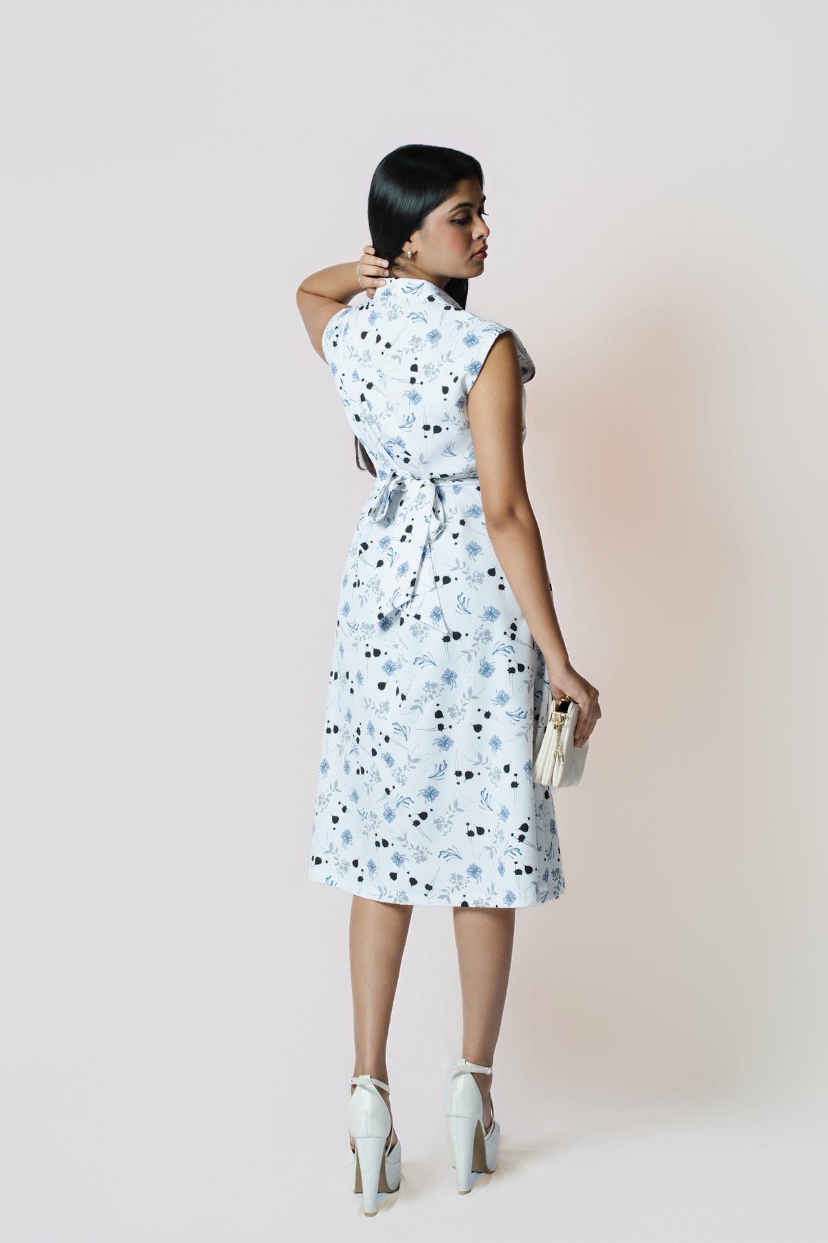 Petal Whirl Belted Dress: white sleeveless collared midi shirt dress with a scattered blue-black petal print and tie belt, back view showing the tie belt