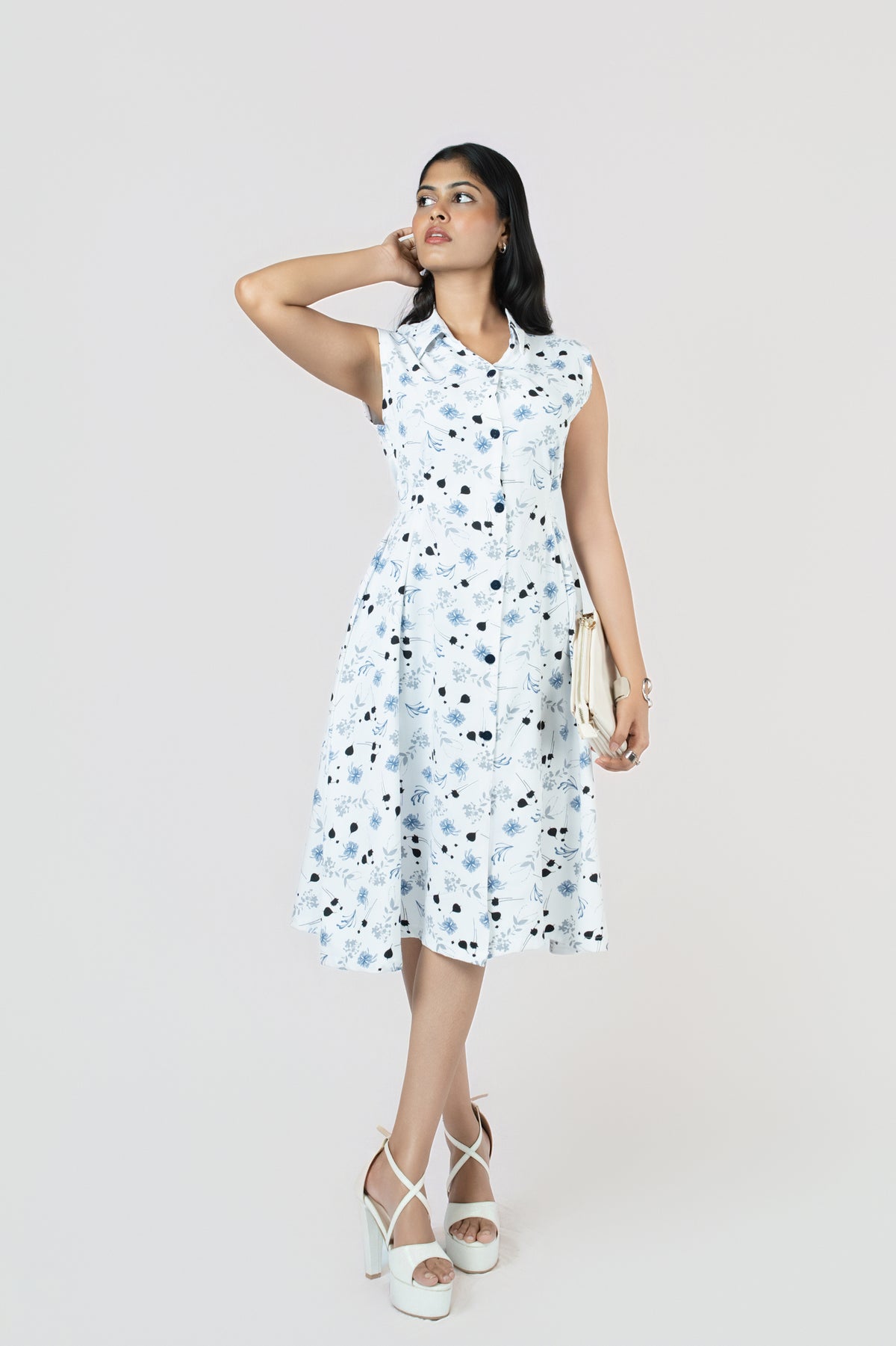 Petal Whirl Belted Dress: white sleeveless collared midi shirt dress with a scattered blue-black petal print and tie belt, front view, posed