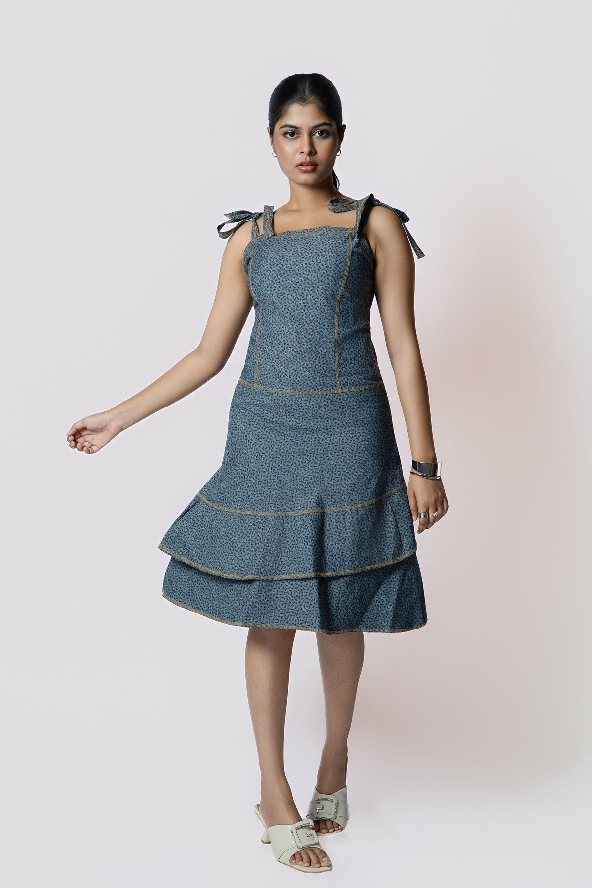 Indigo Whisper Tiered Dress: denim-blue sleeveless dress with tie shoulder straps and a tiered ruffle hem, front view, walking