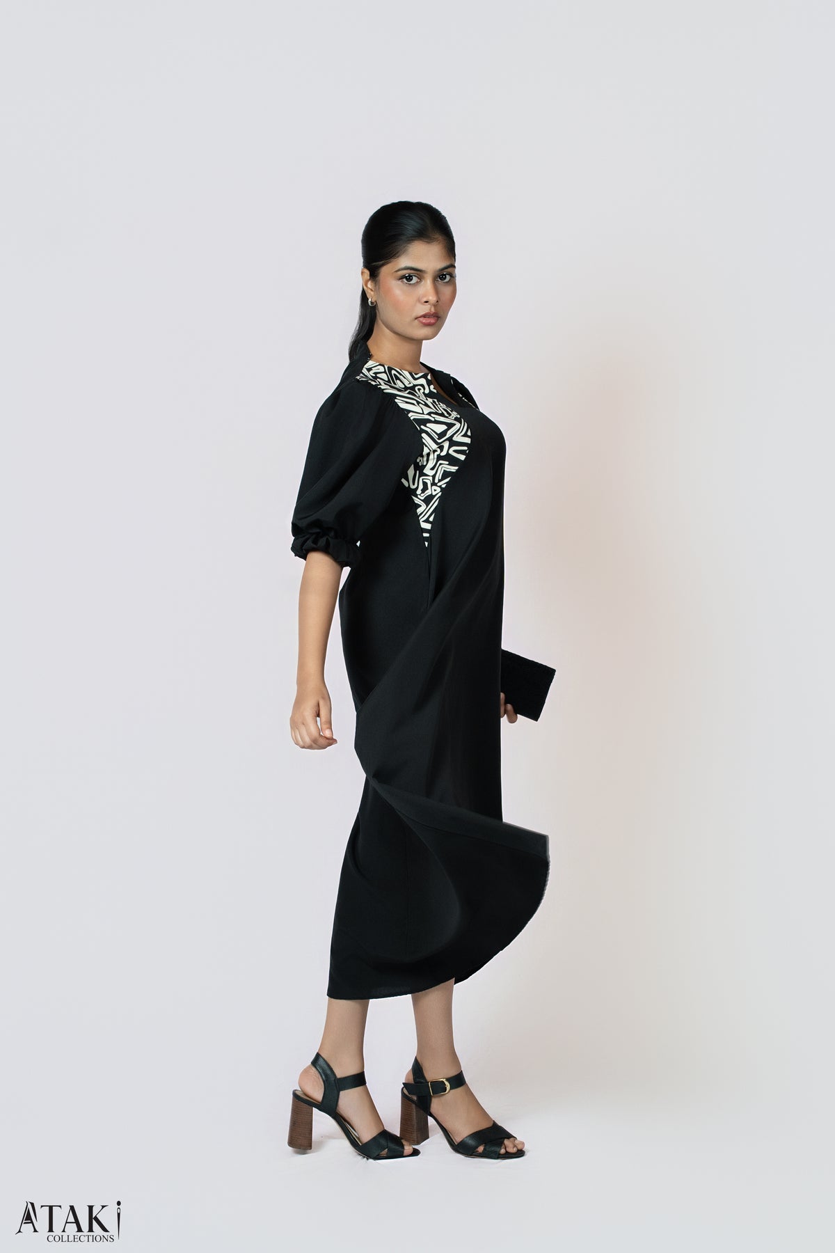 Model in a black puff-sleeve midi dress with a black and white printed neckline