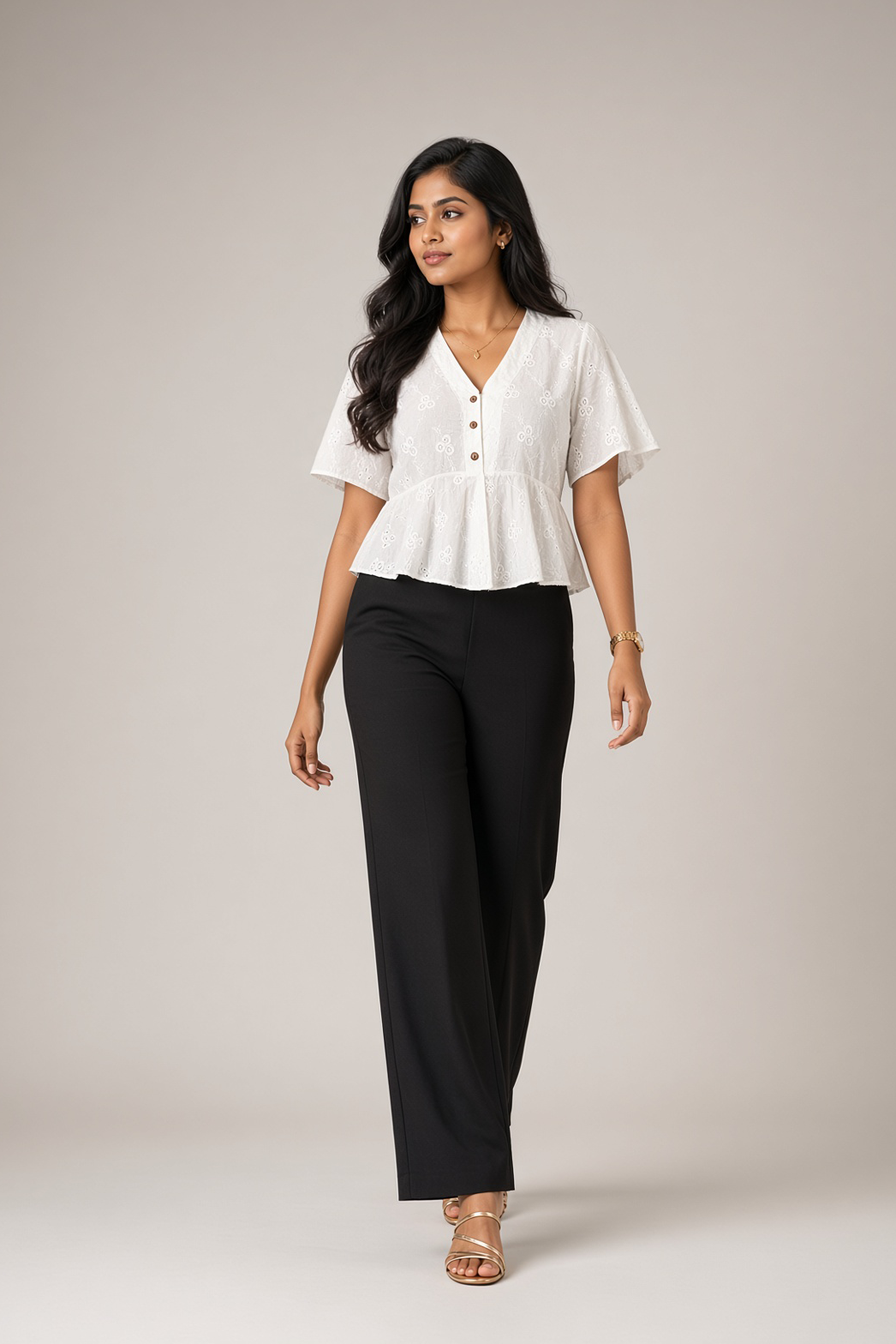 Petal Eyelet Top: white cotton eyelet peplum top with a V-neck and flutter sleeves, worn with black trousers, front view, three-quarter angle