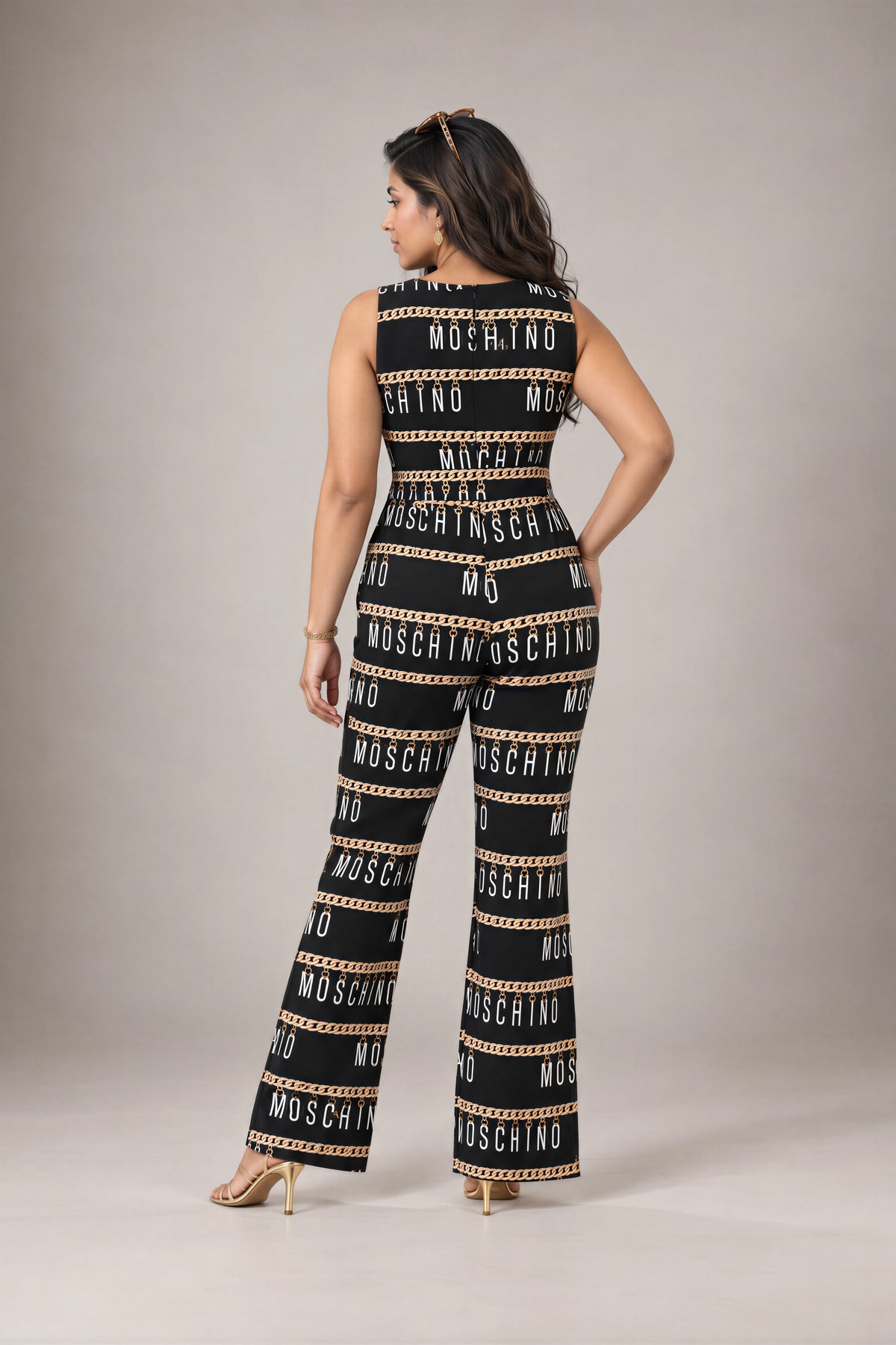 Chain Link Jumpsuit: black sleeveless flared-leg jumpsuit with a gold chain and lettering print, back view